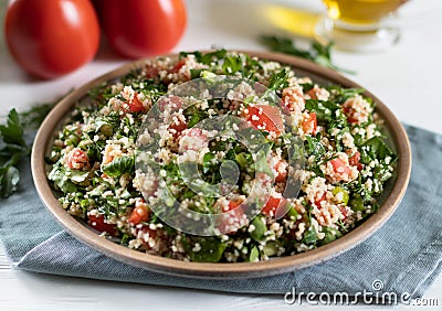 Ceramic plate of Arabic salad Tabbouleh on a white background with gray textiles Stock Photo