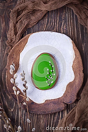 Ceramic plate, gingerbread Easter egg and willow branches on a dark background. Top view Stock Photo