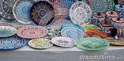 Ceramic plates, hand-painted with a dot pattern, are on the counter at the festive fair. Editorial Stock Photo