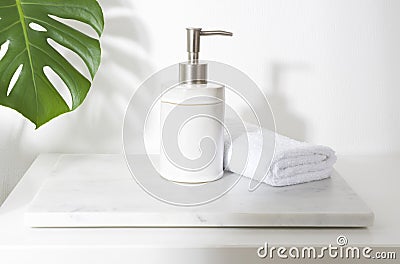 Ceramic soap dispenser and folded towel on white marble stand Stock Photo