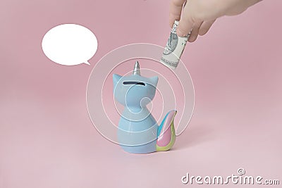 Ceramic souvenir toy money box kitten Korn blue with colorful rainbow tail with unicorn horn on pink background in Stock Photo