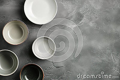 Ceramic tableware on grey background. Various ceramic dishes, plates, bowls, flatware on table. Empty table setting with multiple Stock Photo