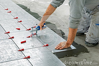 Ceramic Tiles. Tiler placing ceramic wall tile in position over adhesive with lash tile leveling system Stock Photo