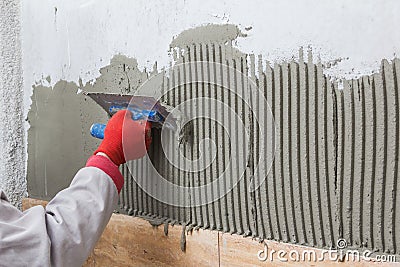 Ceramic Tiles. Tilerman hand spreading adhesive material Stock Photo