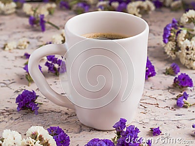 Ceramic white cup of coffee with dry white and violet flowers on the light background. Morning americano. Cafe and bar Stock Photo