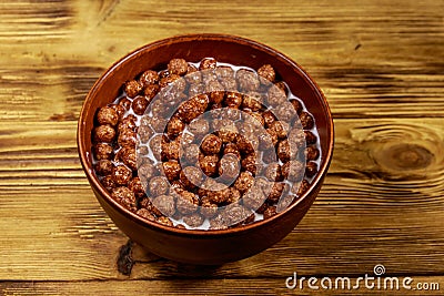 Cereal chocolate balls with milk in a bowl on wooden table Stock Photo