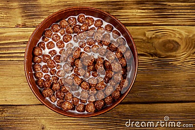 Cereal chocolate balls with milk in a bowl on wooden table. Top view Stock Photo