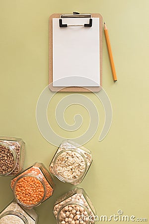 Cereals in glass jars on the table next to a Notepad and pencil. Space for text, white sheet of paper. Stock Photo