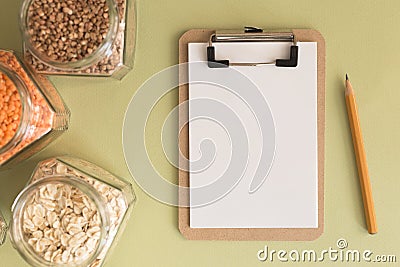 Cereals in glass jars on the table next to a Notepad and pencil. Space for text, white sheet of paper. Stock Photo