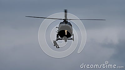Helicopter rescues rescuer and injured person with winch on a bad weather day Editorial Stock Photo