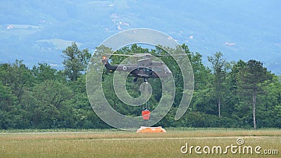 Fire helicopter fills the bambi bucket with water while hovering over a tank Editorial Stock Photo