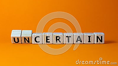 Certain or uncertain symbol. Turned wooden cubes and changed the concept word uncertain to certain. Beautiful orange table, orange Stock Photo