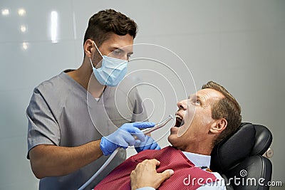 Certified dentist treating his patient at the clinic Stock Photo