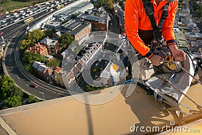 Certifies rope access high rise worker licences using yellow ascender descending with low stretch abseiling rope over the edge Stock Photo