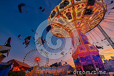 Chain carusel with silhouttes of people having fun at the Oktoberfest in Munich. Editorial Stock Photo