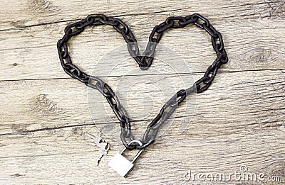 Chain heart shape on the lock on wooden background. Stock Photo