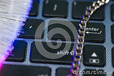 Chain on laptop computer keyboard, glowing optical fibres Stock Photo