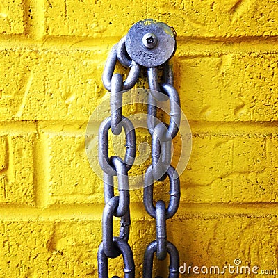 Chain on a yellow brick wall Stock Photo