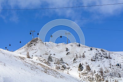 Chair ski lift with skiers over blue sky. Panorama of snow moun Stock Photo