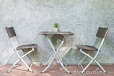 Chair and table on wood patio and loft wall in background Stock Photo