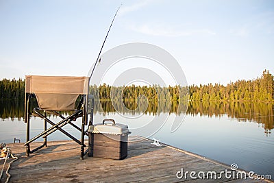 A Chair on a Wooden Dock Looking Out on a Lake in Summer with Fishing Equipment Stock Photo