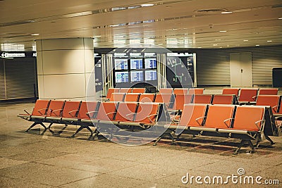 Chairs for passengers in the empty hall of Guangzhou Airport. The sign says `gate locationÂ» and the flight schedule China. Stock Photo