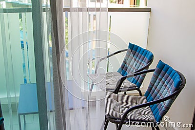 Chairs and table in the balcony behind panoramic window with transparent tulle Stock Photo