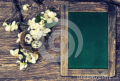 Chalkboard, flowers and easter nest with eggs on wooden backgrou Stock Photo