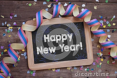 Chalkboard with paper streamers and confetti with happy new year 2022 on wooden background Stock Photo