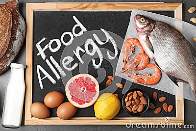 Chalkboard with phrase FOOD ALLERGY and different products on dark grey background Stock Photo