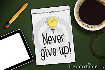 Green chalkboard with sketchbook, tablet and cup of coffee with message Never give up Stock Photo
