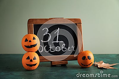 Chalkboard with text 31 OCTOBER and oranges painted for Halloween on table Stock Photo