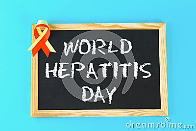 Chalkboard with text World Hepatitis Day. June 28th. Red yellow ribbon on a blue background. Stock Photo