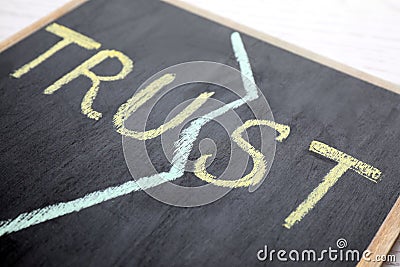 Chalkboard with word TRUST on white table. Concept of jealousy Stock Photo