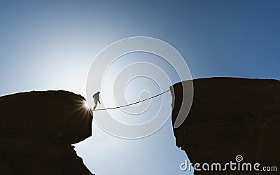 Challenge, risk, concentration and bravery concept. Silhouette a man balance walking on rope over precipice Stock Photo