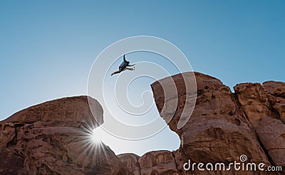 Challenge, risk and freedom concept. Silhouette a man jumping over precipice crossing cliff Stock Photo