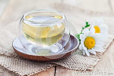 Chamomile tea in glass cup, chamomile flowers on background Stock Photo