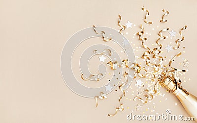 Champagne bottle with confetti stars and party streamers on gold festive background. Christmas, birthday or wedding. Flat lay Stock Photo