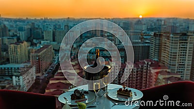 Champagne bottle and glasses, cake at restaurant with sunset Editorial Stock Photo