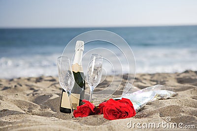 Champagne Bottle, Glasses, Roses at the beach Stock Photo