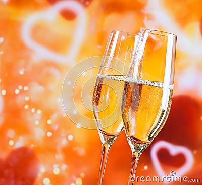 Champagne flutes with golden bubbles on blur decorative hearts background Stock Photo