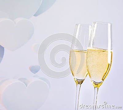 Champagne flutes with golden bubbles on blur decorative hearts background Stock Photo