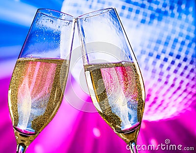 Champagne flutes with golden bubbles make cheers on sparkling blue and violet disco ball background Stock Photo