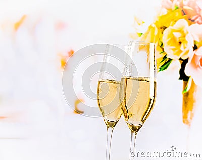 Champagne flutes with golden bubbles on wedding flowers background Stock Photo