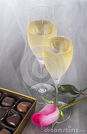 Champagne Flutes, Gourmet Chocolates, and a Pink Rose on Gray Tulle Background Stock Photo