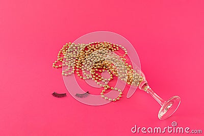 Champagne glass with golden pearls and eyelashes on pink background. Creative minimal New Year paty celebration concept. Stock Photo