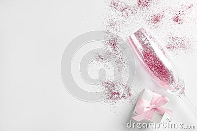 Champagne glass with pink glitter, gift box and space for text on white background. Hilarious celebration Stock Photo