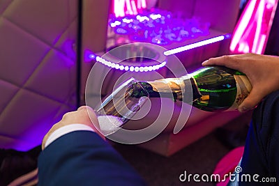 Hand fills champagne flutes in the limusine with back light Stock Photo