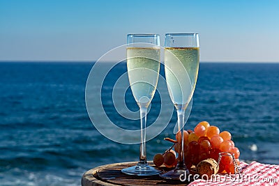 Champagne, prosecco or cava served with pink grape in two glasses on outside terrace with sea view Stock Photo