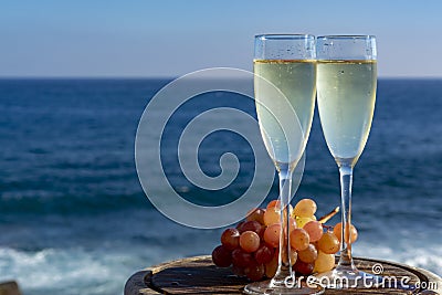Champagne, prosecco or cava served with pink grape in two glasses on outside terrace with sea view Stock Photo
